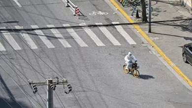  عامل صحة بملابس واقية يعبر شارعا في شنغهاي على دراجة خلال تدابير إغلاق في 8 أبريل 2022
